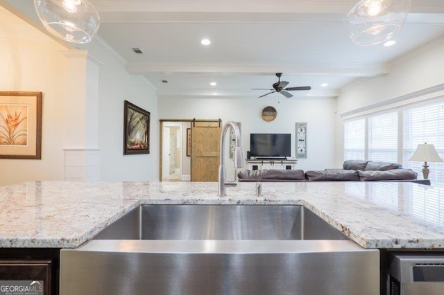 kitchen featuring beam ceiling, visible vents, a barn door, and a sink