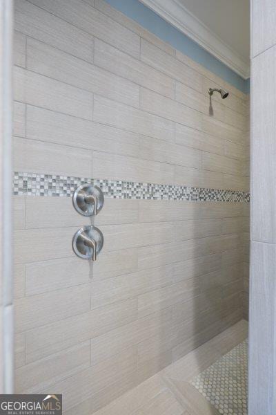 bathroom with crown molding and a tile shower