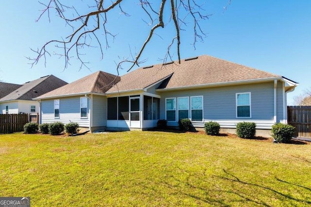 back of property with a yard, a sunroom, roof with shingles, and fence