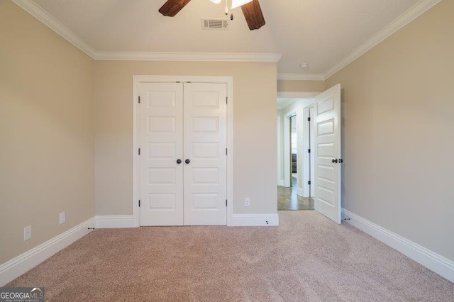 unfurnished bedroom featuring a closet, baseboards, crown molding, and carpet