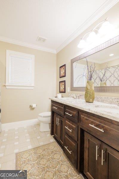 bathroom with a sink, visible vents, toilet, and double vanity