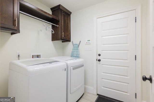 washroom with cabinet space, washing machine and dryer, and light tile patterned flooring