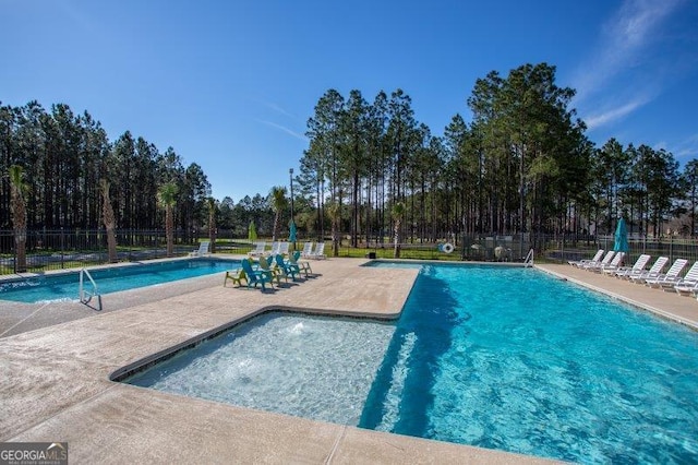 community pool with a patio area and fence