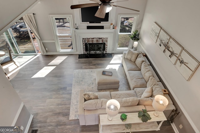 living room with baseboards, a ceiling fan, wood finished floors, and a fireplace