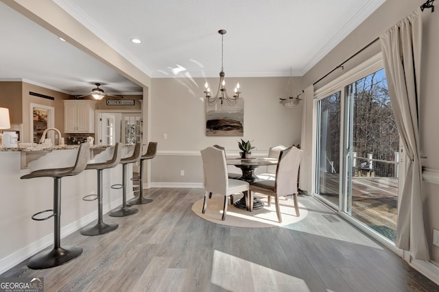 dining space with crown molding, light wood-style flooring, and baseboards