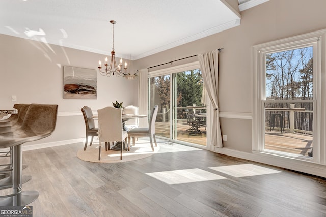 dining area with a chandelier, crown molding, baseboards, and wood finished floors