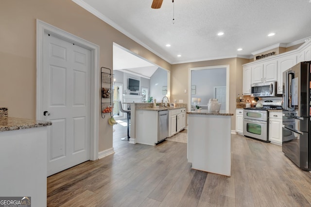 kitchen featuring a sink, a textured ceiling, white cabinetry, appliances with stainless steel finishes, and light wood finished floors