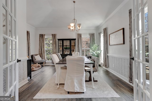 dining area featuring dark wood finished floors, french doors, wainscoting, crown molding, and a chandelier