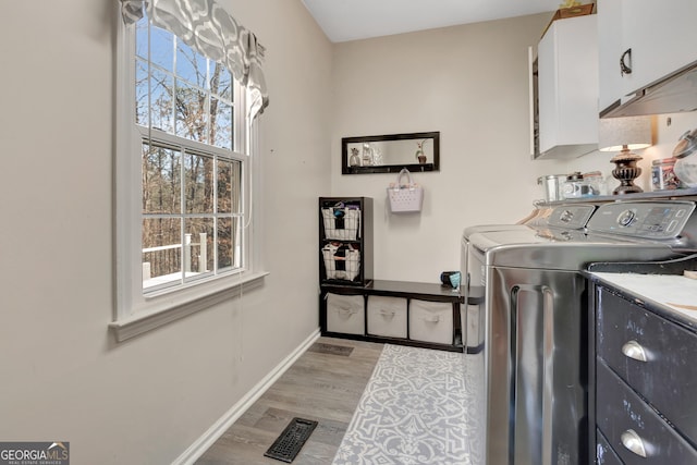 laundry room featuring baseboards, visible vents, light wood-style flooring, cabinet space, and washer and clothes dryer