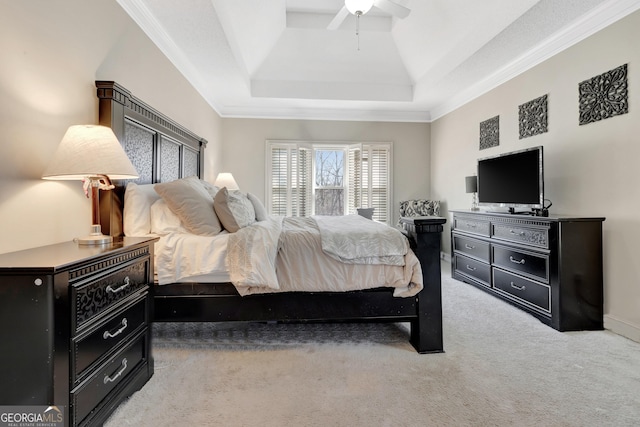 bedroom with a ceiling fan, baseboards, a tray ceiling, crown molding, and light colored carpet