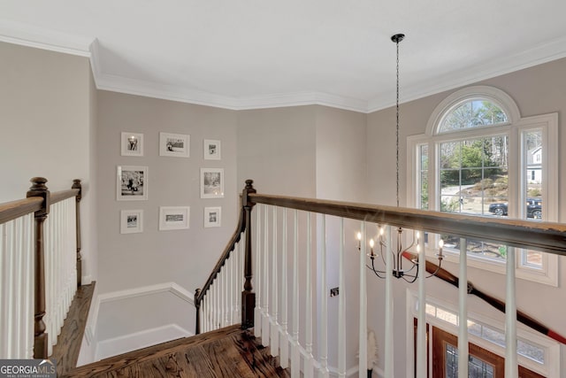 stairs with crown molding, wood finished floors, baseboards, and a chandelier