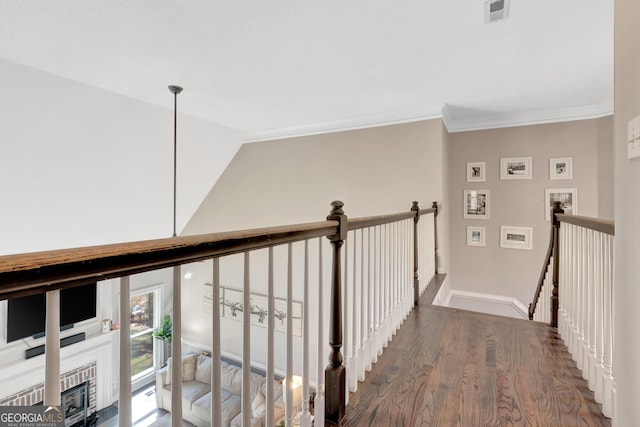 hall with visible vents, an upstairs landing, wood finished floors, crown molding, and baseboards