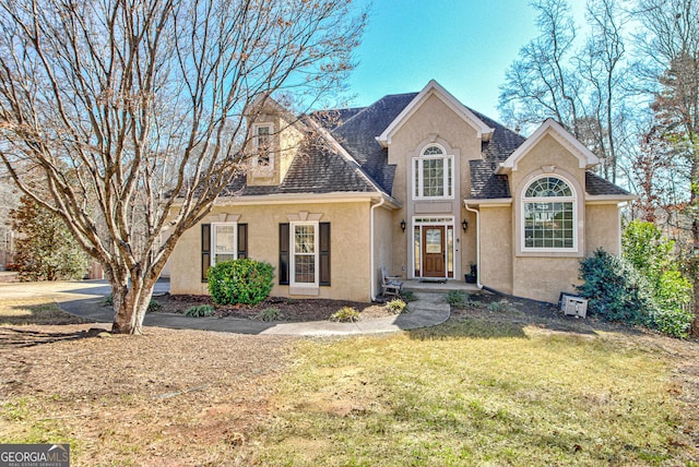 view of front of house featuring stucco siding, a front lawn, and roof with shingles