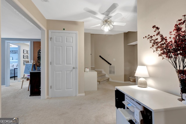 office space with visible vents, light carpet, baseboards, and ceiling fan