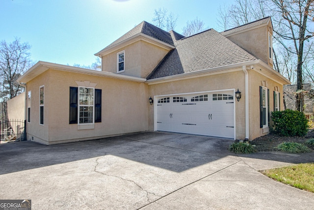 view of front of home featuring stucco siding, an attached garage, concrete driveway, and roof with shingles