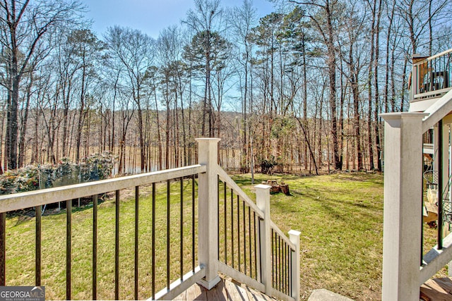 wooden terrace with a lawn and a view of trees