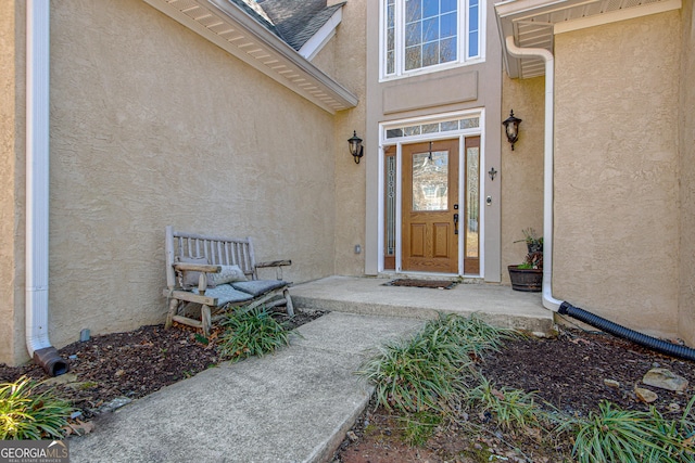 property entrance featuring stucco siding and roof with shingles