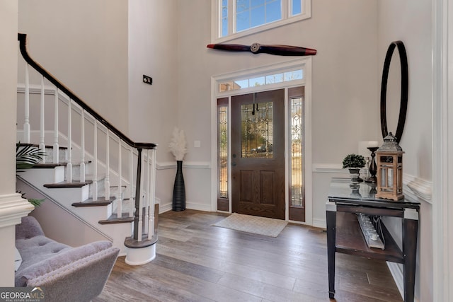 foyer entrance featuring stairs, a high ceiling, baseboards, and hardwood / wood-style floors