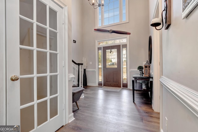 entrance foyer featuring stairway, a high ceiling, a chandelier, and hardwood / wood-style flooring