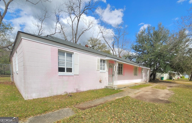 view of front facade with concrete block siding and a front lawn