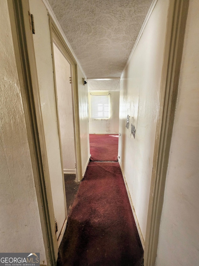 hall with a textured ceiling, ornamental molding, and carpet flooring