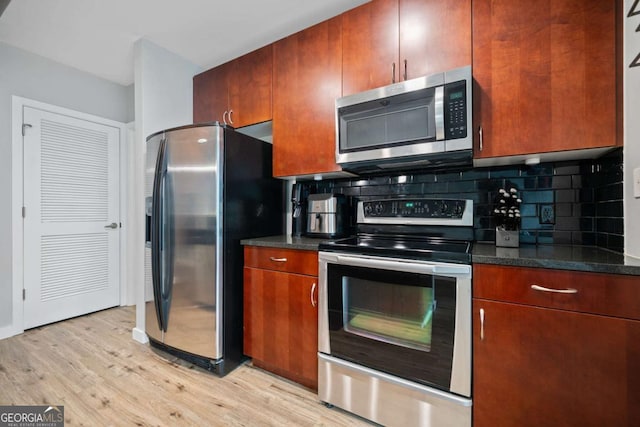 kitchen featuring backsplash, appliances with stainless steel finishes, light wood-type flooring, and dark stone countertops