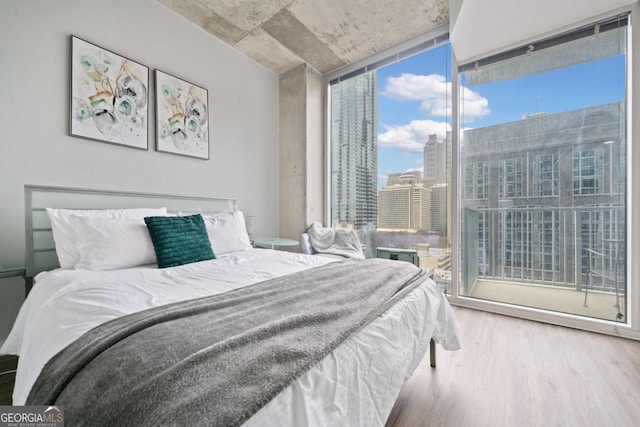 bedroom featuring a wall of windows, a city view, and wood finished floors