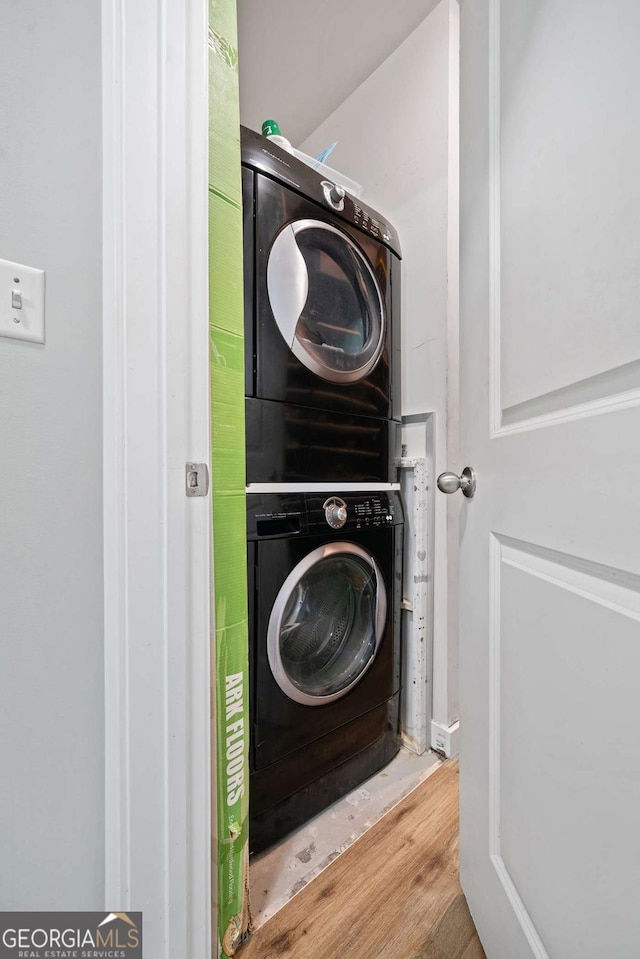 laundry room with laundry area, stacked washing maching and dryer, and wood finished floors