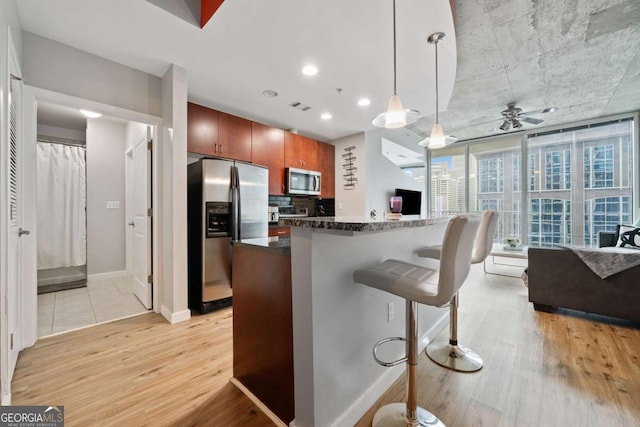 kitchen featuring light wood finished floors, backsplash, stainless steel appliances, and dark countertops