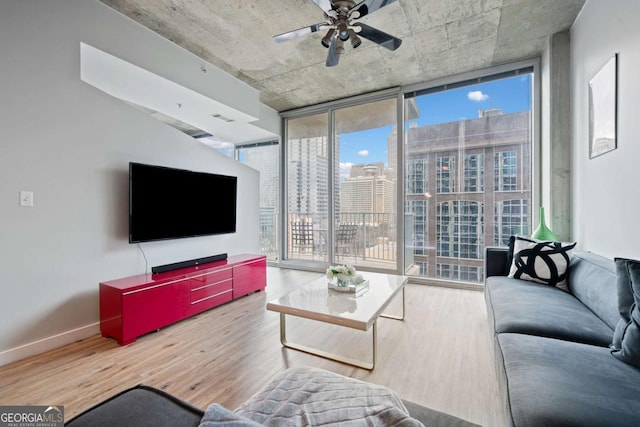 living room with baseboards, a ceiling fan, wood finished floors, and floor to ceiling windows