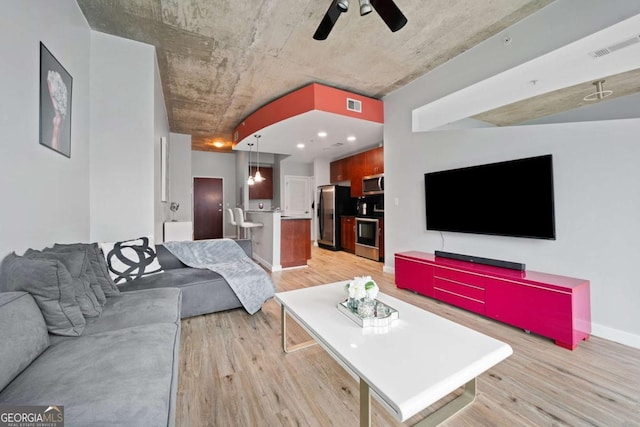 living room with visible vents, baseboards, light wood-style flooring, and a ceiling fan