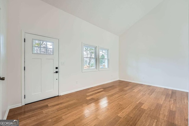 foyer featuring light wood-style flooring, a healthy amount of sunlight, baseboards, and high vaulted ceiling