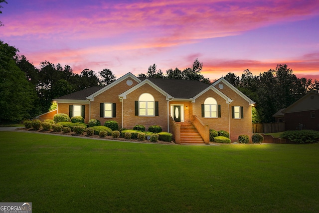 single story home featuring brick siding, a front lawn, and fence