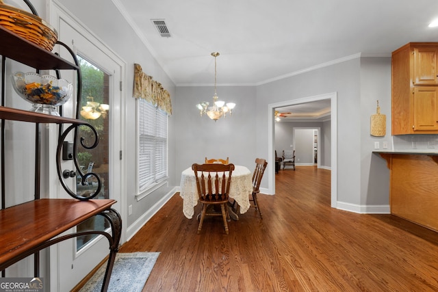 dining room featuring visible vents, wood finished floors, crown molding, baseboards, and a chandelier