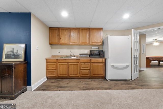 kitchen with dark wood finished floors, stainless steel microwave, freestanding refrigerator, and a sink