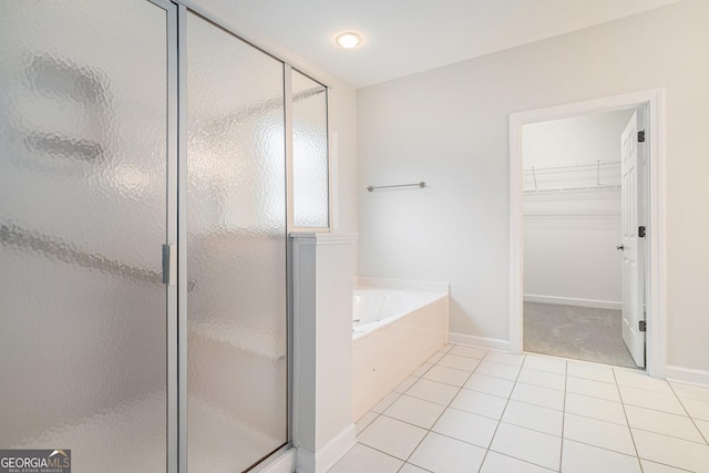 bathroom with a bath, tile patterned floors, a stall shower, and a walk in closet