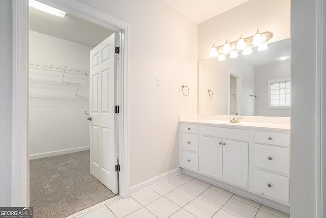 full bath with a spacious closet, tile patterned flooring, vanity, and baseboards