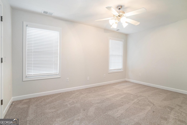 unfurnished room featuring baseboards, light colored carpet, visible vents, and ceiling fan