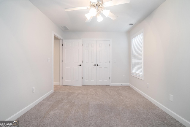 unfurnished bedroom featuring visible vents, light colored carpet, baseboards, and a closet