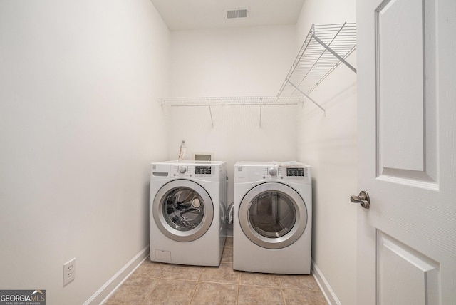 clothes washing area with visible vents, baseboards, washing machine and dryer, light tile patterned floors, and laundry area