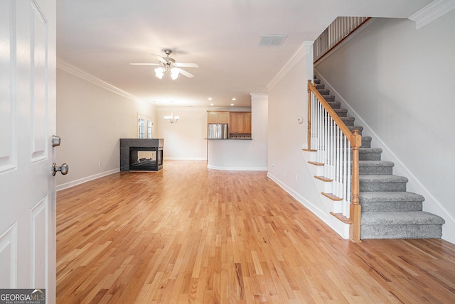 unfurnished living room with stairway, visible vents, light wood finished floors, and ornamental molding