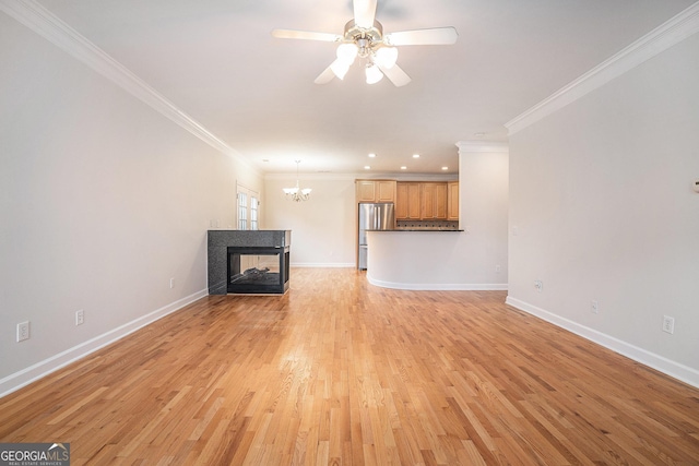 unfurnished living room with ceiling fan with notable chandelier, light wood-style floors, baseboards, and ornamental molding