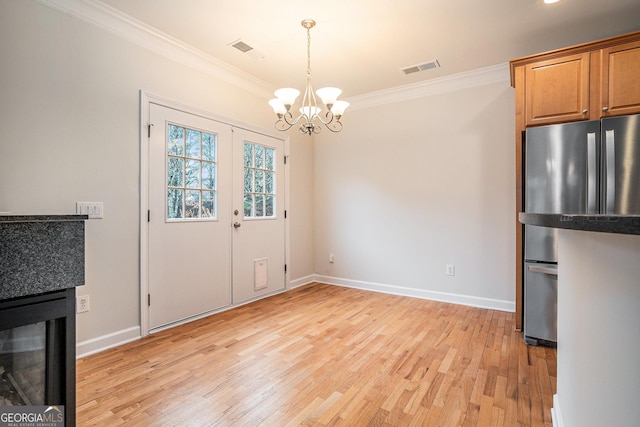 unfurnished dining area featuring a notable chandelier, baseboards, crown molding, and light wood-style floors