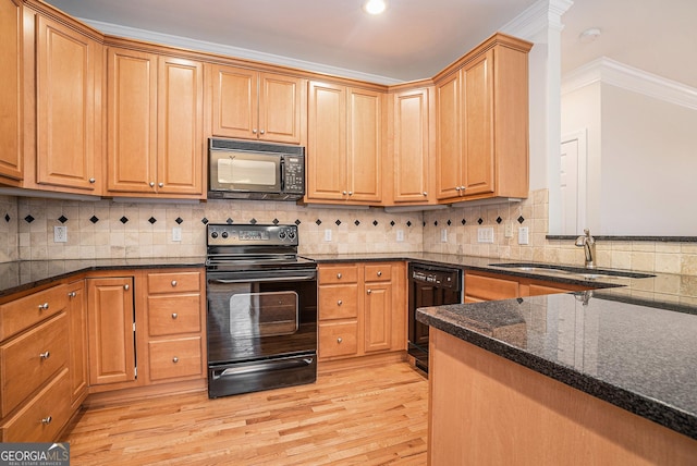 kitchen featuring light wood-type flooring, black appliances, a sink, backsplash, and dark stone counters