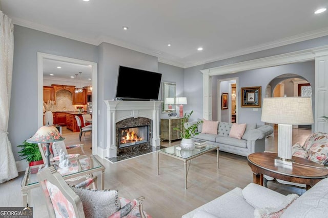 living area with recessed lighting, ornamental molding, a fireplace, and wood finished floors