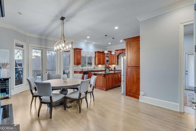 dining space with light wood finished floors, baseboards, ornamental molding, french doors, and a notable chandelier