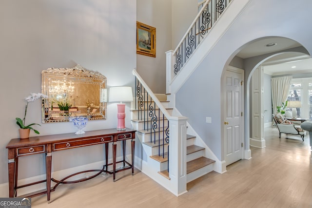 3845 Starboard Pt, Gainesville, GA 30506 - staircase featuring wood finished floors, a towering ceiling, arched walkways, and baseboards