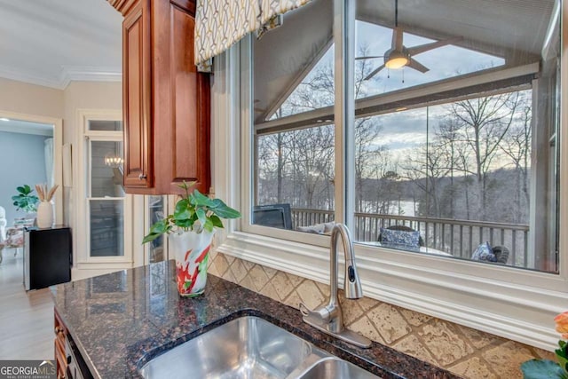 kitchen featuring a sink, plenty of natural light, brown cabinetry, and ornamental molding