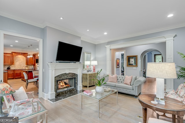 3845 Starboard Pt, Gainesville, GA 30506 - living area featuring light wood-style flooring, a premium fireplace, recessed lighting, arched walkways, and crown molding