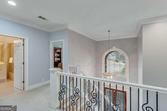 hallway with visible vents, an upstairs landing, baseboards, and crown molding